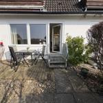 Terrasse mit Tisch und Stühlen vor einem Haus mit Glastür.