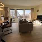 Wohn- und Essbereich mit Sofa, TV und großem Fenster zur Außenterrasse.