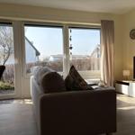 Wohnzimmer mit Sofa, TV und Fenstern zum Garten