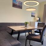 Essbereich mit Holztisch, Sitzbank und Stühlen. An der Wand hängen Bilder.