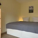 Schlafzimmer mit Bett, Stehlampe und Wandbild