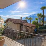 Balkon mit Blick auf Palmen und Berge unter blauem Himmel.