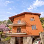 Orangefarbener zweistöckiger Wohnbau mit Balkonen und Gartenzaun.