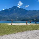 Volleyballplatz am See mit Bergen im Hintergrund.
