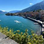 Blick auf einen See mit Booten und einem Dorf an der Küste.