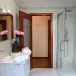 Badezimmer mit Dusche, Waschbecken und Spiegel. Rosa Rosen im Vase.