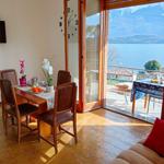 Esszimmer mit Blick auf See und Berge. Terrasse mit Tisch und Stühlen.