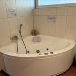 Eckwhirlpool mit Dusche und Kerzen. Anweisungen an den Wänden.