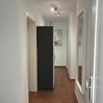 Flur mit braunen Fliesen, schwarzer Garderobe und Wandbild mit Segelbooten.