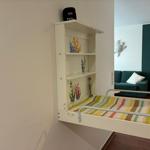 Wandbett mit Regal und Korallenmotiven, dahinter Sofa und Wanddekoration.