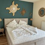 Schlafzimmer mit Bett, Nachttisch und Wanddekoration.