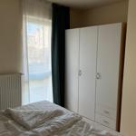 Schlafzimmer mit Bett, Kleiderschrank und Fenster mit Blick auf die Straße.