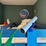 Ein Kinderzimmer mit blauem Bett, Seekopfposter und Fernglas an der Matratze.