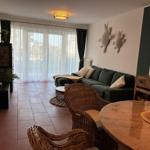 Wohnzimmer mit Sofa, Esstisch und Fenster mit Gardinen.