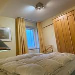Schlafzimmer mit Bett, Kleiderschrank und Fenster mit Vorhängen.