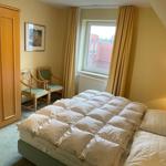 Schlafzimmer mit Doppelbett, Kleiderschrank und Fenster mit Blick auf Dächer.