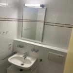 Badezimmer mit Waschbecken, Spiegel und Handtuchhalter.