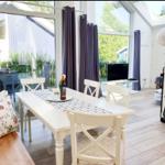 Essbereich mit weißem Tisch und Stühlen, großes Fenster und Blick auf Garten.