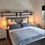 Schlafzimmer mit Doppelbett, Nachttischen und Stehlampe unter schrägem Dach