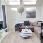 Wohnzimmer mit Sofa, Fernseher und Deckenfenstern.