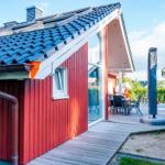 Rotes Holzhaus mit Terrasse und Sitzgelegenheiten.