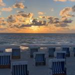 Strand mit Strandkörben und Sonnenuntergang über dem Meer.