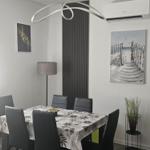 Esszimmer mit Tisch, Stühlen und moderner Deckenleuchte.