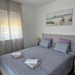 Schlafzimmer mit Doppelbett, Wandbild und Fenster mit Jalousie.