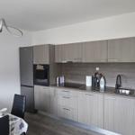 Moderne Küche mit Küchenzeile, Spüle und Kühlschrank. Essbereich mit Tisch und Stühlen.