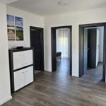 Wohnbereich mit dunklen Türen und Holzboden. An der Wand hängen zwei Bilder.