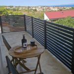 Terrasse mit Tisch und Stühlen, Blick auf Landschaft und Meer.
