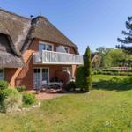 Haus mit Strohdach, Balkon und Garten mit Tisch und Stühlen.