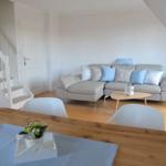 Wohn- und Essbereich mit Sofa, Tisch und Stühlen. Hintergrund: Treppe und Tür.