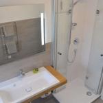 Badezimmer mit Dusche, Waschbecken und Spiegel