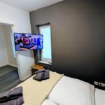Schlafzimmer mit Bett, Fernseher und Blick in Wohnbereich.