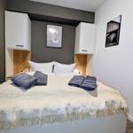 Schlafzimmer mit Bett, weißen Kabinen und Kunst an der Wand.