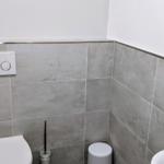 Badezimmer mit Toilette, Spüle und Mülleimer an der Wand.