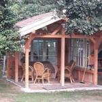Wooden covered area with chairs and windows under trees