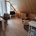 Living room with wooden ceiling, sofa, TV, and desk.