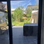 Deck with wooden bench and view of green garden