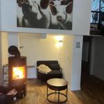 Living area with wood stove, sofa, and wall painting of pigs.