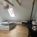 Bedroom with sloped ceiling, bed, desk, and hanging chair.