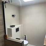 Bathroom with shower, toilet, and sink on wooden countertop.