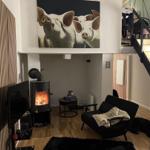 Living area with fireplace, armchair, and wall painting of pigs.