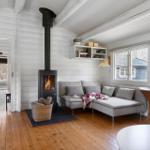 Living room with fireplace, sofa, and wooden floor. Kitchen in background.
