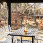 Patio with table and chairs, featuring a bottle and bowl of strawberries.