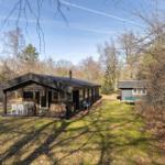 Wooden house with terrace, garden, and small outbuilding in woodland.