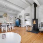 Living and dining area with fireplace, wooden floor, and white wood paneling.