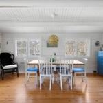 Dining room with wooden floor, white table, blue seat cushions, and blue cabinet.
