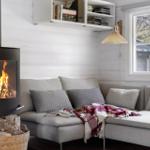 Living room with sofa, fireplace, and window overlooking trees.